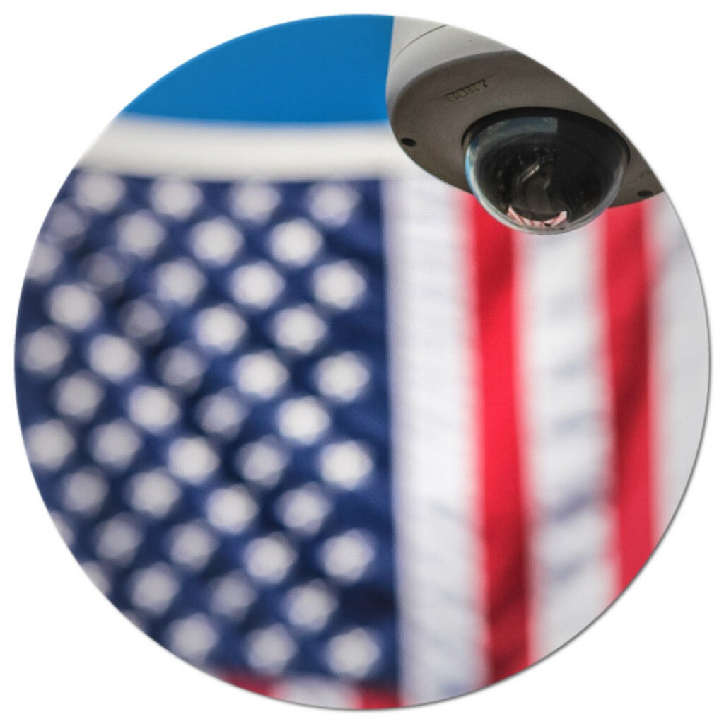 A cctv camera with an american flag in the background.