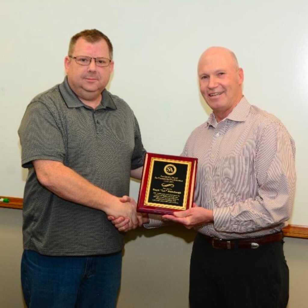 A person handing over an award to a person and smiling